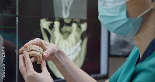 Orthopedic dentist doctor holds teeth 3d printed model of the patient's jaw on x-ray background photo