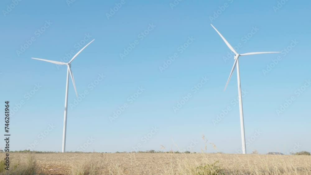 On a mountain farm windmill turbines symbolize clean energy innovation. Sustainable development thrives with modern wind technology against the backdrop of a blue sky. On a mountain farm windmill turbines symbolize clean energy innovation. Sustainable development thrives with modern wind technology against the backdrop of a blue sky.