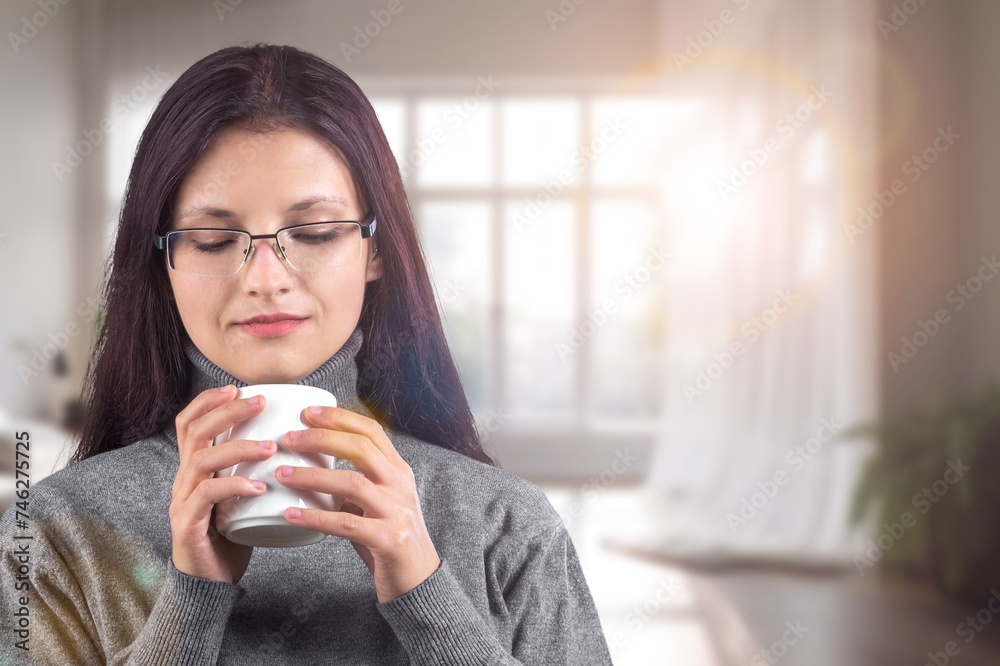 A young woman holding a cup of tea or coffee