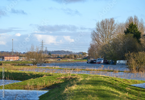 Grass flood bank and rising river water © simonXT2