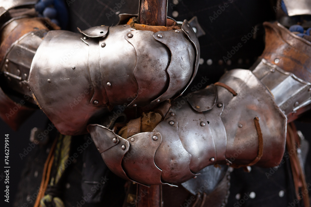 Hands of a medieval knight in iron protective gauntlets holding a spear close-up. Part of the military uniform. Historical reconstruction Hands of a medieval knight in iron protective gauntlets holding a spear close-up. Part of the military uniform. Historical reconstruction