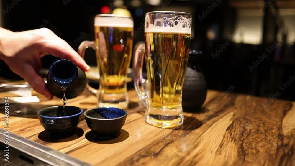 Pouring Sake into Cups Beside Beer Pouring Sake into Cups Beside Beer