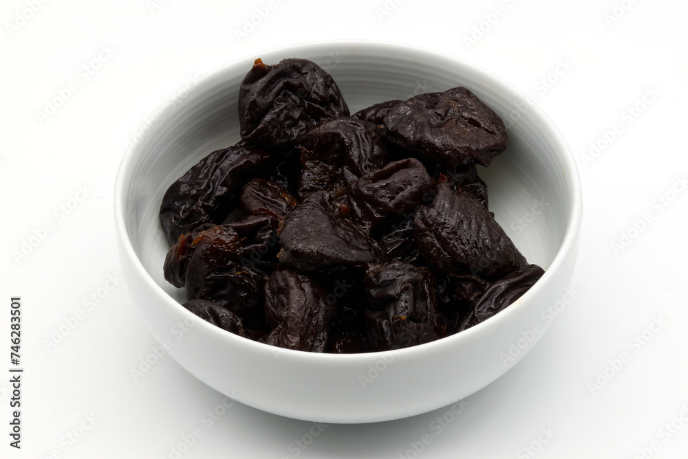 Dried plums in a white bowl isolated on white background Dried plums in a white bowl isolated on white background