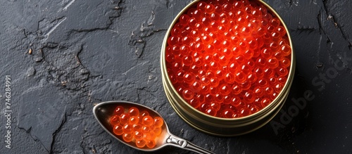 A top-down view of an empty tin can masquerading as red caviar, alongside a spoon, in an unoccupied setting.