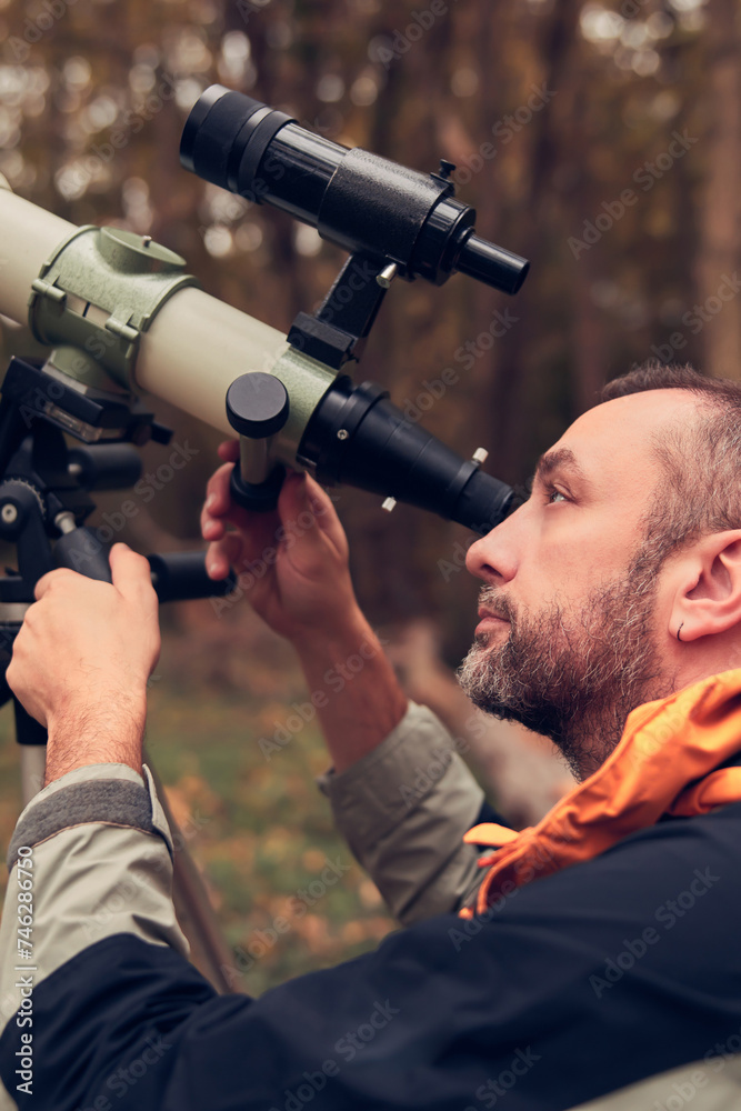 man using telescope for bird and animal watching in nature.