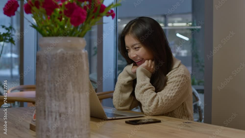 Young pretty asian Chinese girl talks happily and smiles during online call in cafe. Young pretty asian Chinese girl talks happily and smiles during online call in cafe.