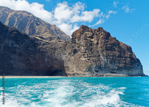 View from a tourist boat of an amazing cliff  with cave entrance in the Pacific ocean at Napali Coast, Island of Kauai, Hawaii photo