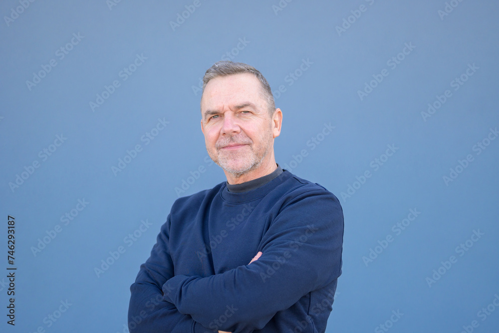 Close up portrait of a middle aged man looking friendly with his arms folded Close up portrait of a middle aged man looking friendly with his arms folded