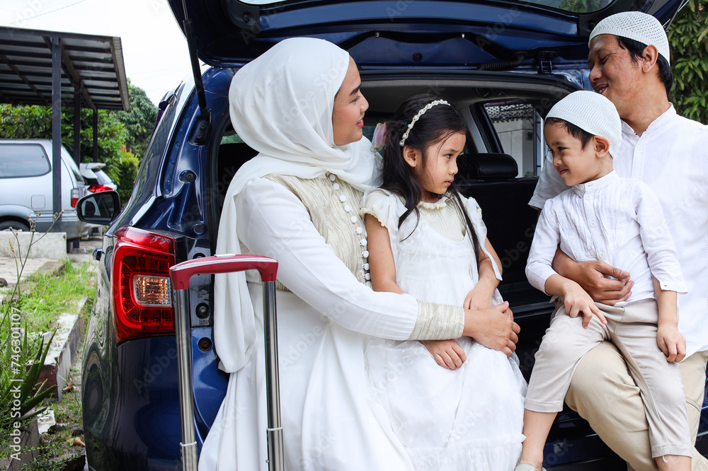 Happy Muslim family sitting in the car trunk ready to go on holiday. Mudik lebaran at Eid moment. Happy Muslim family sitting in the car trunk ready to go on holiday. Mudik lebaran at Eid moment.