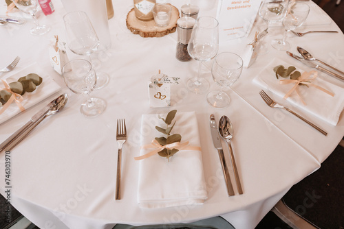 Coziness and style. Modern event design. Table setting at wedding reception. Floral compositions with beautiful flowers and greenery, candles, laying and plates on decorated table photo
