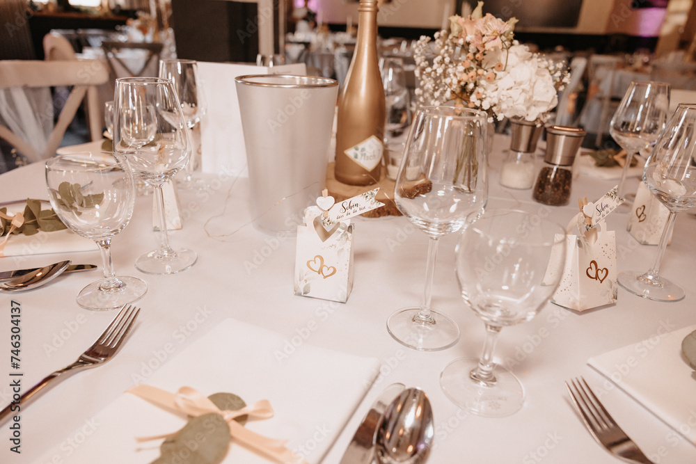 Coziness and style. Modern event design. Table setting at wedding reception. Floral compositions with beautiful flowers and greenery, candles, laying and plates on decorated table