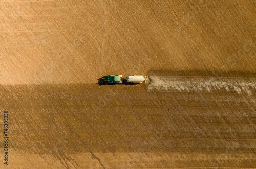 Aerial overhead image of a tractor irrigating a crop field in summer. Dry land due to lack of rain. Hot summer. No crop. Mediterranean countries suffer from drought and heat. Concept climate change.