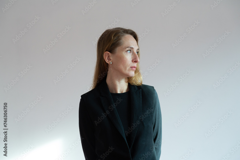 Portrait in profile of an adult young woman in a black suit on a white background Portrait in profile of an adult young woman in a black suit on a white background