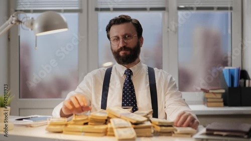 Wealth, earnings, career concept. Successful man in expensive office sits at desk in front of pile of dollars. Vain and arrogant banker, broker or lawyer enjoys earnings. Businessman looking at camera photo