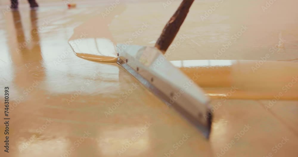 Slow-motion of a  worker applying a primer support layer for epoxy resin with a floor squeegee