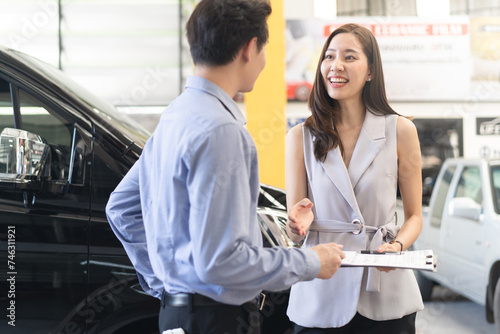 Woman car salesperson showing finance contract to client and explain deal in auto showroom