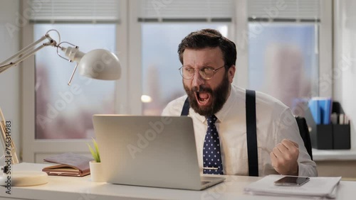 Rage, scream, failure concept. Irritated and aggressive man shouts at computer being very upset after bad news. Mad office worker is furious photo