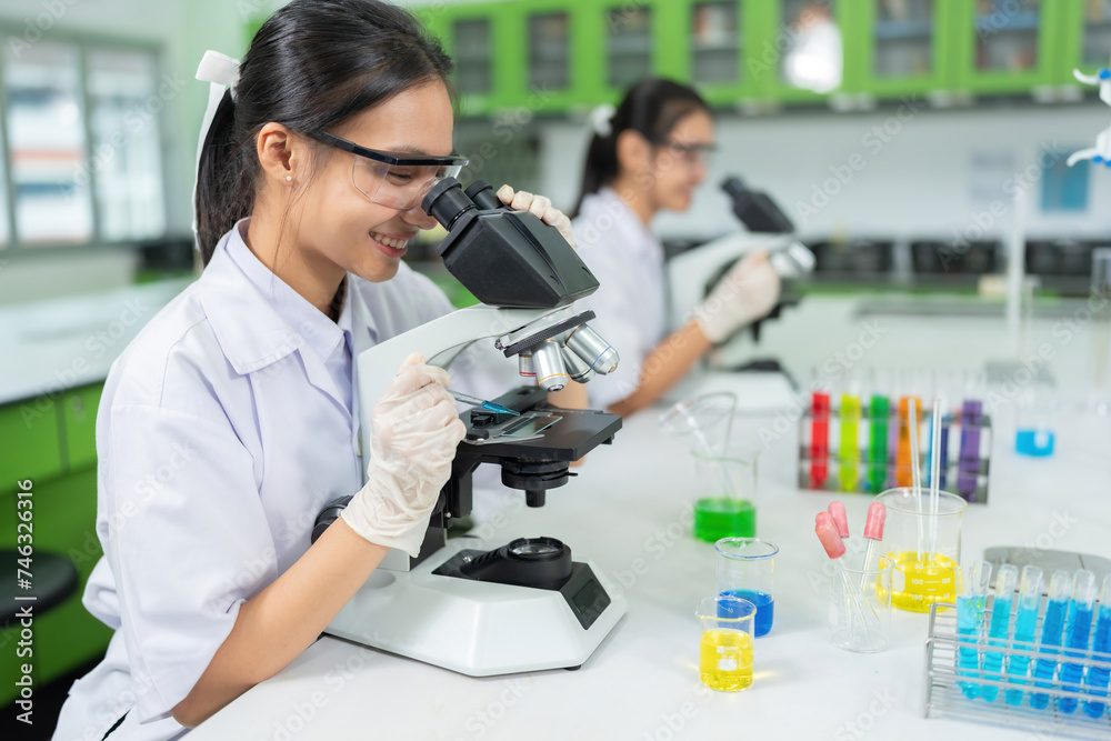In a pharmaceutical factory, 2 Asian female scientists use microscopy to conduct medical research, chemical cells for industrial businesses, companies and hospitals, making vaccines to treat patients. In a pharmaceutical factory, 2 Asian female scientists use microscopy to conduct medical research, chemical cells for industrial businesses, companies and hospitals, making vaccines to treat patients.