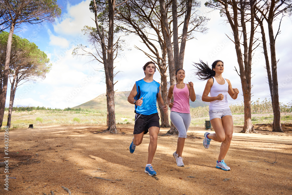 Fitness, group or friends in nature running for exercise, training or outdoor workout together. People, fast runners or athletes at a park for sports endurance, wellness or cardio challenge in woods Fitness, group or friends in nature running for exercise, training or outdoor workout together. People, fast runners or athletes at a park for sports endurance, wellness or cardio challenge in woods
