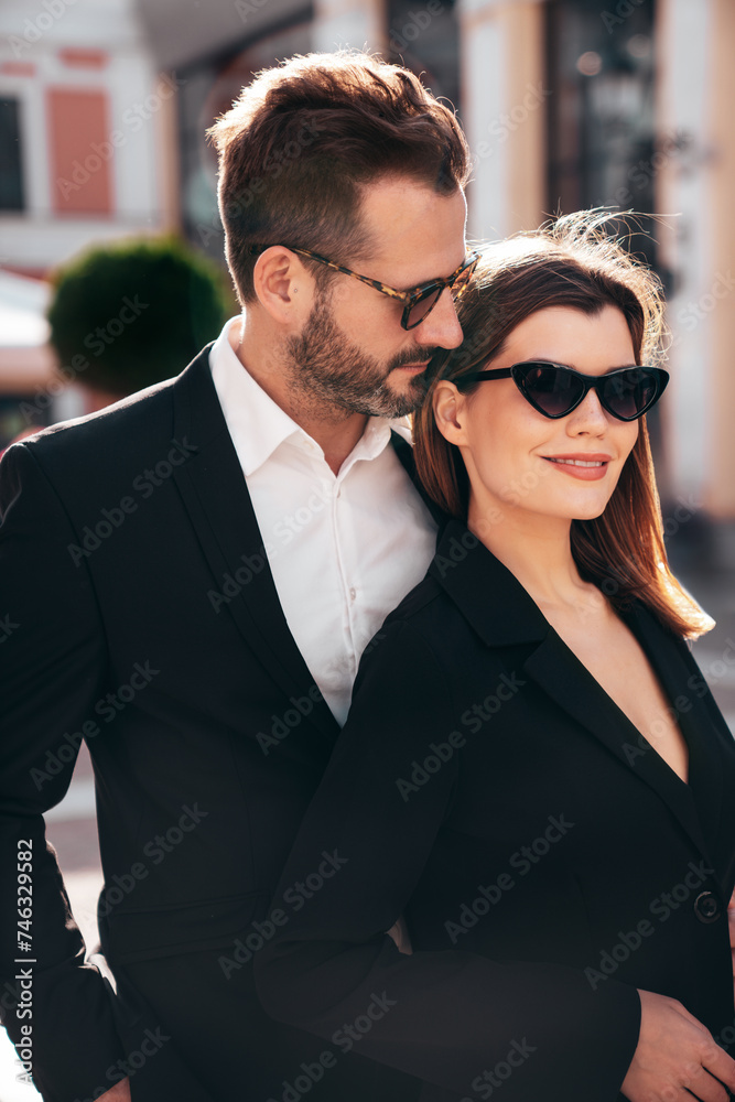 Beautiful fashion woman and her handsome elegant boyfriend in black suit. Sexy brunette model in jacket. Fashionable confident couple posing in street. Brutal man and female outdoors. In sunglasses Beautiful fashion woman and her handsome elegant boyfriend in black suit. Sexy brunette model in jacket. Fashionable confident couple posing in street. Brutal man and female outdoors. In sunglasses