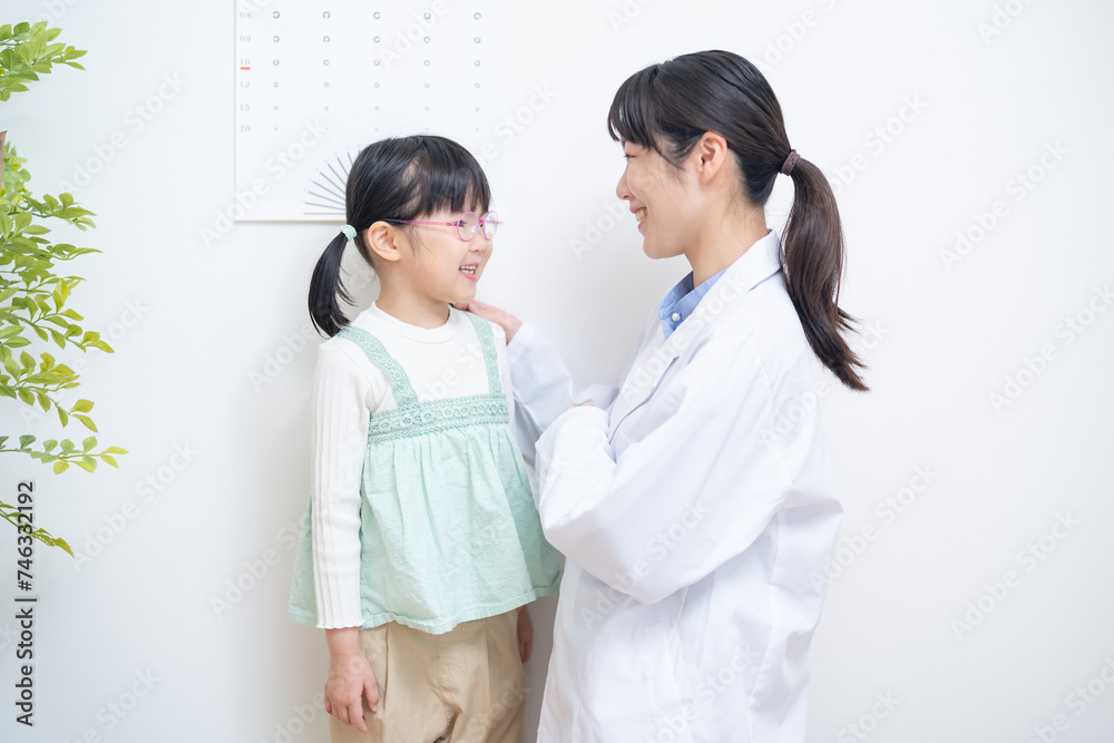 視力検査表の前で話す女性医師と女の子 視力検査表の前で話す女性医師と女の子