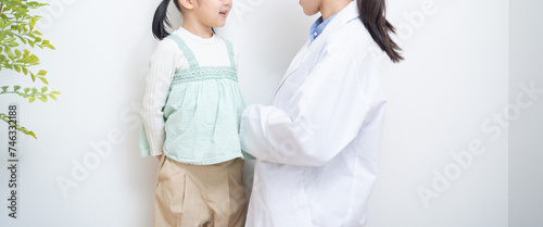 視力検査表の前で話す女性医師と女の子
