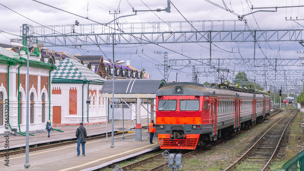 Electric transport on the railway. Contact power lines for commuter trains. People get on an electric train on the platform. Railway tracks at the railway station.Transportation of passengers by train