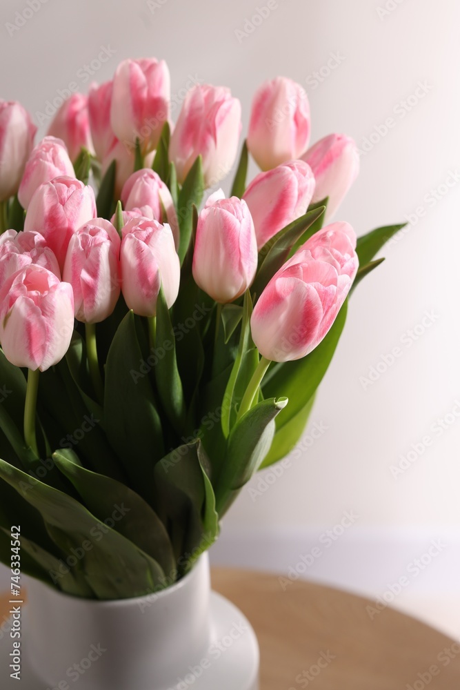 Beautiful bouquet of fresh pink tulips on table against light background, closeup