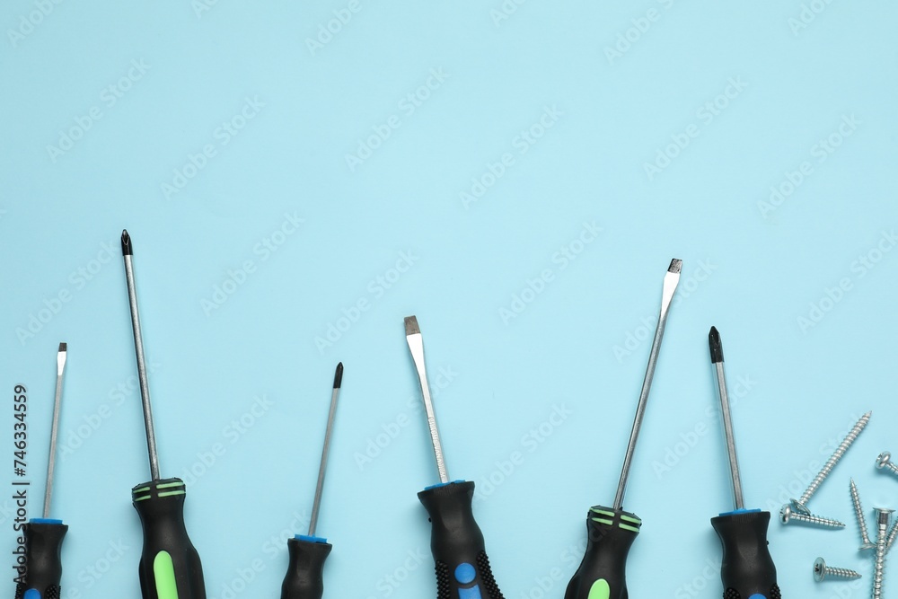 Set of screwdrivers and screws on light blue background, flat lay. Space for text Set of screwdrivers and screws on light blue background, flat lay. Space for text