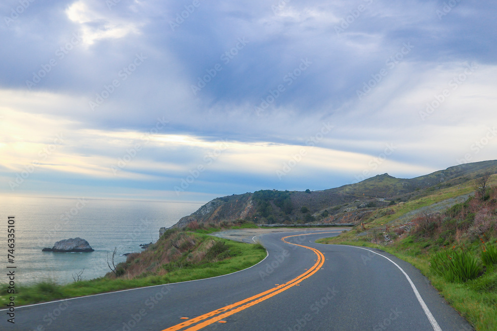 It's a scenic route, perfect for a relaxing road trip that offers stunning views of the ocean. It captures the calming essence of a leisurely drive along the coast. Coastal Road Car Journey. 