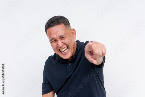 A middle-aged man laughing and pointing at someone off camera, making a mockery of someone, isolated on a white background.