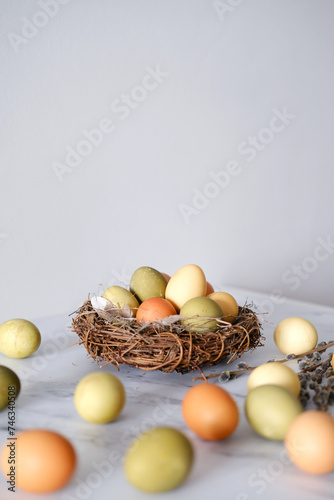 Close-up of a nest of twigs inside with yellow, green and light green easter eggs