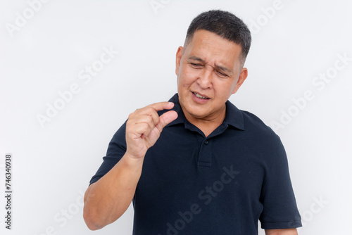 A middle-aged Asian man squints and gestures something very small with his hands, isolated on a white background. Ridiculing and belittling someone's manhood photo