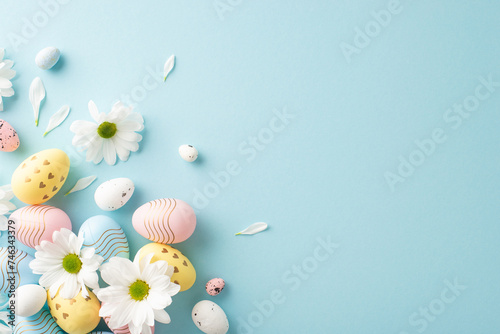 Easter fantasy depiction. Top view of decorated eggs, and tender blossoms on a pastel blue setting with a blank space for creative texts or promotions