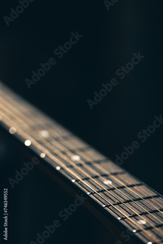 Part of an acoustic guitar, guitar fretboard on a black background.