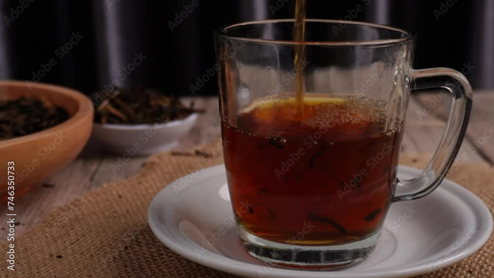 pouring tea into clear glass with ornament dried tea leaves pouring tea into clear glass with ornament dried tea leaves