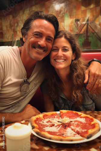 Young mature couple enjoy night at the pizzeria having a picture in front of a margherita pizza at the table. People and romantic dating. Man and woman eating italian food for dinner