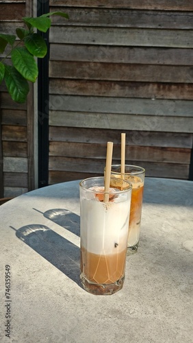A glasses of milk coffee on cement table outdoor with sunlight. Summer drink