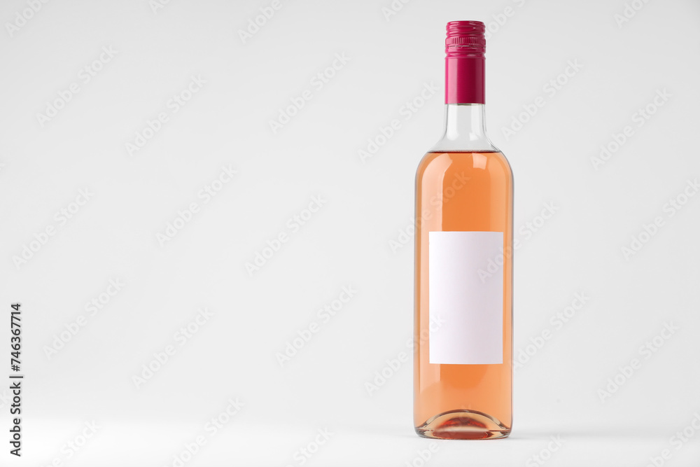 Bottle of tasty rose wine on white background, space for text