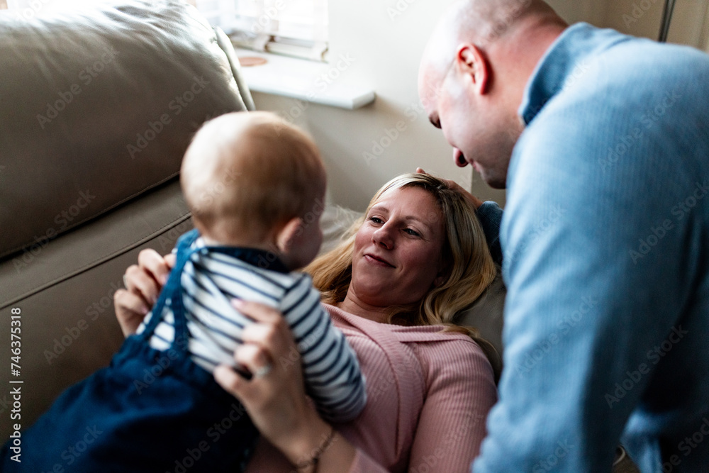 Obraz premium Happy family portrait with parents laughing and looking at their son