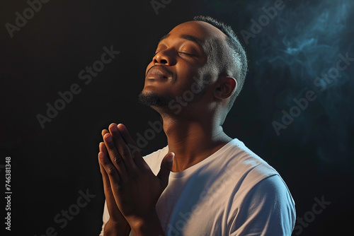 African American Man prays to god on black studio background