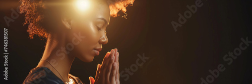 African American woman prays to god on dark studio background. Cinematic effect