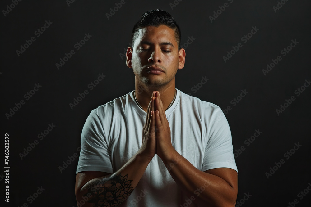 Latin American man prays to god on black studio background