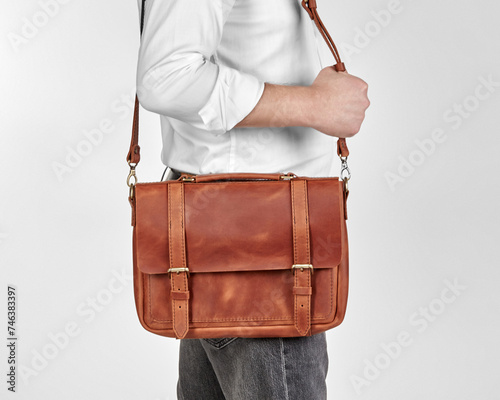 Man carrying copper-colored leather messenger bag over shoulder