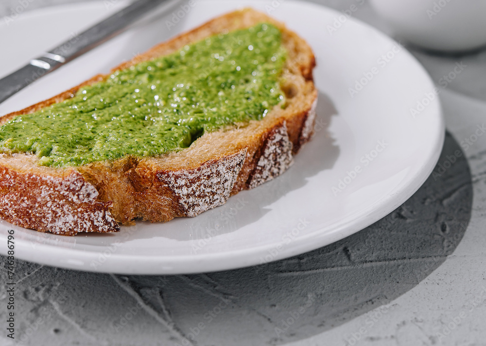 bread with homemade pesto sauce spread with a knife bread with homemade pesto sauce spread with a knife
