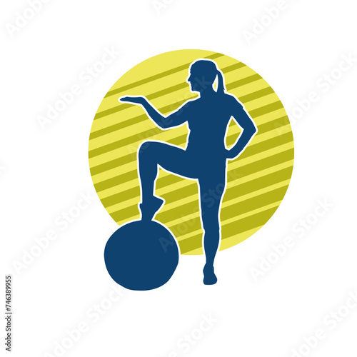 Silhouette of a slim sporty woman doing pilates exercise using gym ball. Silhouette of a sporty female doing physical exercise using fitness ball. 