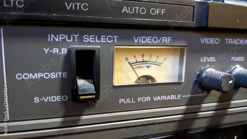 A close-up of a control panel with dials and switches, including a meter with the needle pointing to the middle.