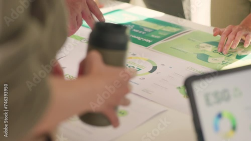 A close-up of a corporate team's hands pointing at ESG sustainability reports, indicating active engagement and analysis.