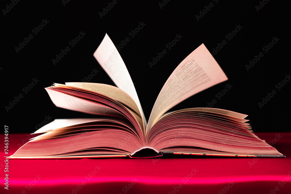 Obraz premium Pages of a thick book are turned on a pink and black background