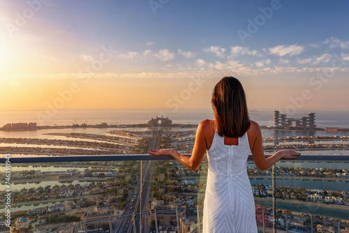 Obraz na płótnie A beautiful woman in a white dress enjoys the sunset view over the Palm in Dubai, UAE w salonie